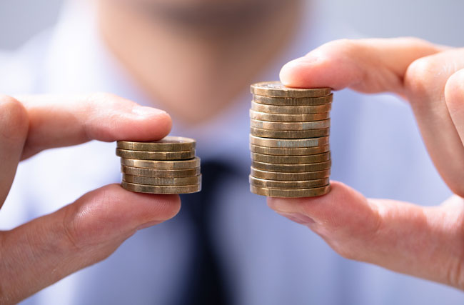 Ein Mann hält zwei unterschiedlich grosse Münzrollen hoch, symbolisch für eine ungerechte Lohnverteilung und fehlende Lohntransparenz und Gleichstellung.