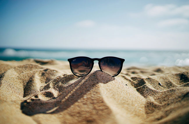 Sonnenbrille auf einem Sandstrand, symbolisch für die Ferienzeit
