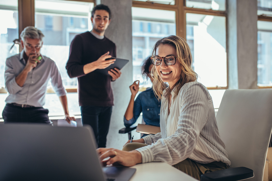 Deux hommes et deux femmes regardent un ordinateur dans un bureau