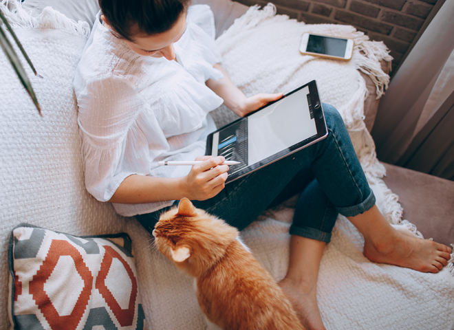 Une femme assise sur un canapé regarde son chat