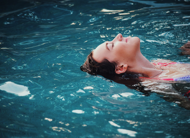 Une femme se détend en flottant dans l'eau sur le dos