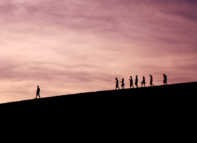 Des personnes en sillhouette sur un pente