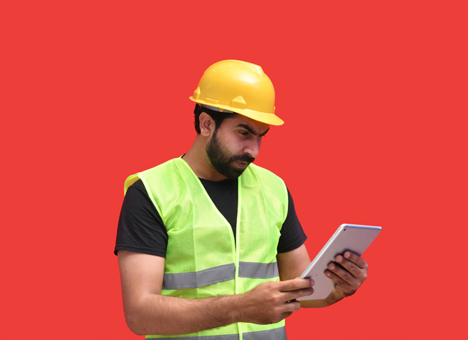 Un homme avec un casque de chantier regarde une tablette