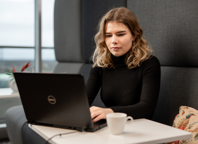 Une femme assise travaille sur un ordinateur portable