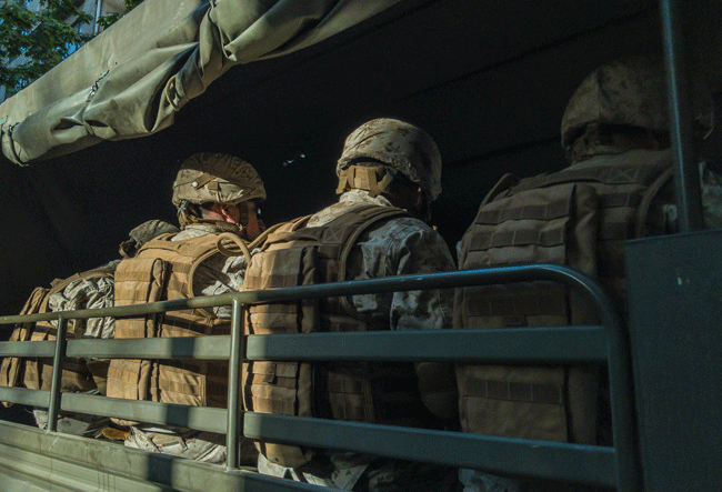 Eine Truppe in Militärausrüstung fährt in einem offenen Militärwagen