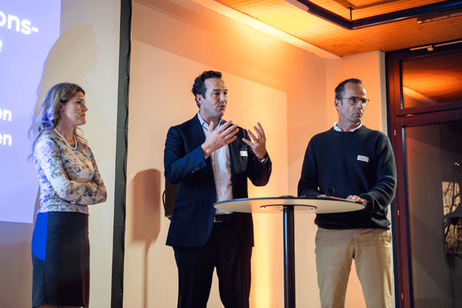 Michèle Mégroz, CSP AG, und Jan Jacob, Manpower Group Schweiz, mit Moderator Alex Koch stehen auf der Bühne und gestikulieren.