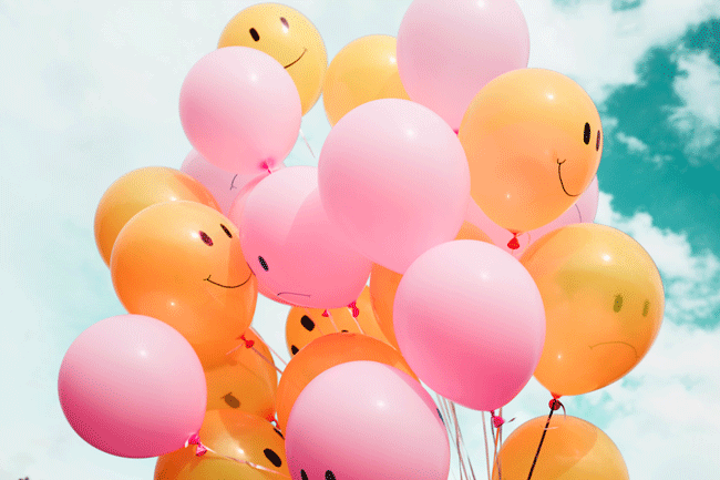 Helium-Ballone mit glücklichen und unglücklichen Gesichtern steigen in den Himmel, symbolisch für Mitarbeiterzufriedenheit