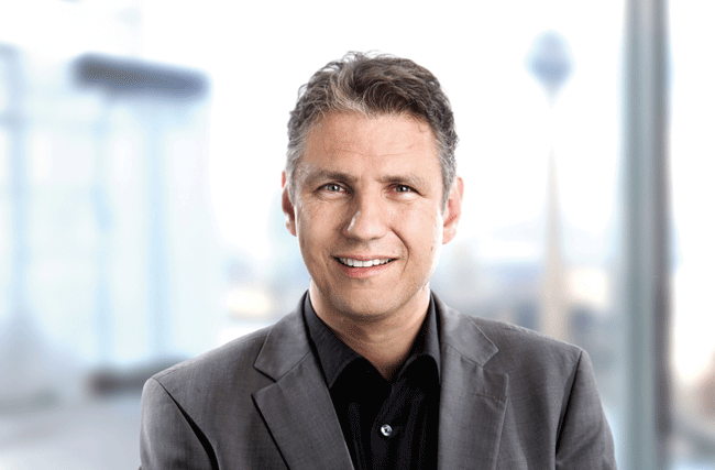 Porträtfoto von Jens Uwe Meyer im grauen Anzug und schwarzem Hemd. Er ist Digitalisierungsexperte und Autor zum Thema KI.