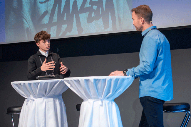 Lernender Noah Kristoffy in angeregter Diskussion mit Marc Marthaler, Head of Next Generation bei Swisscom, über das neue Rekrutierungssystem von Swisscom, das an der Next Talent 2024 vorgestellt wurde.