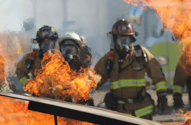 Feuerwehr steht vor einem brennenden Haus, symbolisch für organisationales Burnout