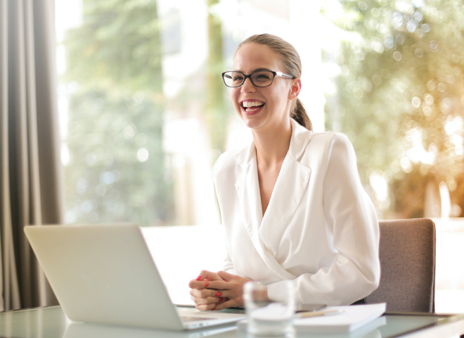 Pourquoi la formation RH avec spécialisation C façonne l'avenir de la location de services: une jeune femme assisse à un bureau, sourit.