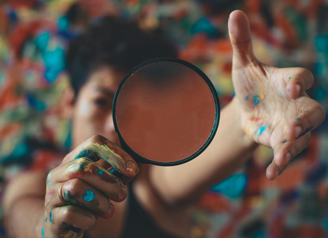 Stimuler sa créativité: une femme avec les mains couvertes de peinture regarde à travers une loupe