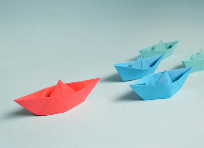 Besoin d'anticipation et qualité de vie au travail: un bateau en papier rouge suivi d'autres bateaux en papier
