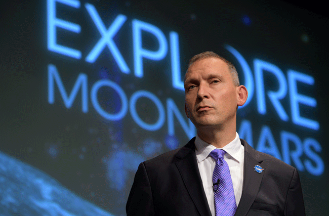 Astrophysiker der NASA und ETH Professor Thomas Zurbuchen steht im Anzug mit einer violetten Krawatte auf der Bühne. Im Hintergrund steht der Spruch "Explore Moon/Mars"
