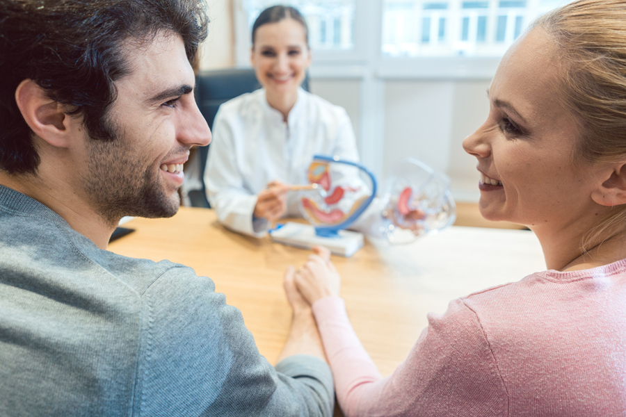 Programmes de fertilité pour employés: un couple souriant se regarde chez un médecin