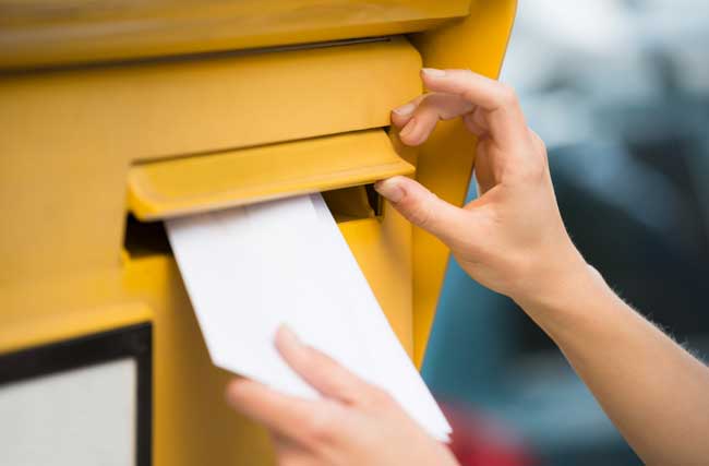 Person steckt einen Kündigungsbrief in einen Briefkasten
