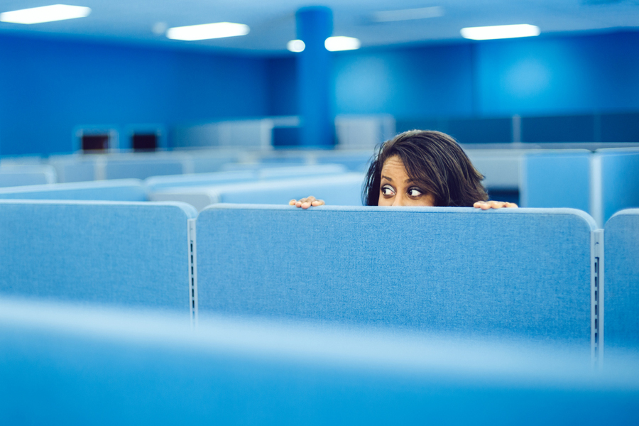 Logiciels de surveillance au travail: contrôle versus confiance. Une femme regarde par-dessus une paroi dans un bureau.