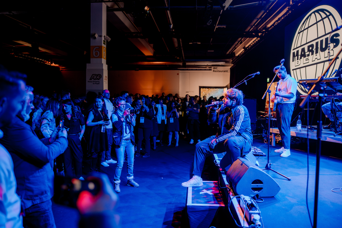 Marius Bear sitzt am Bühnenrand und singt für die Gäste der Break The Norm Party am HR FESTIVAL europe.