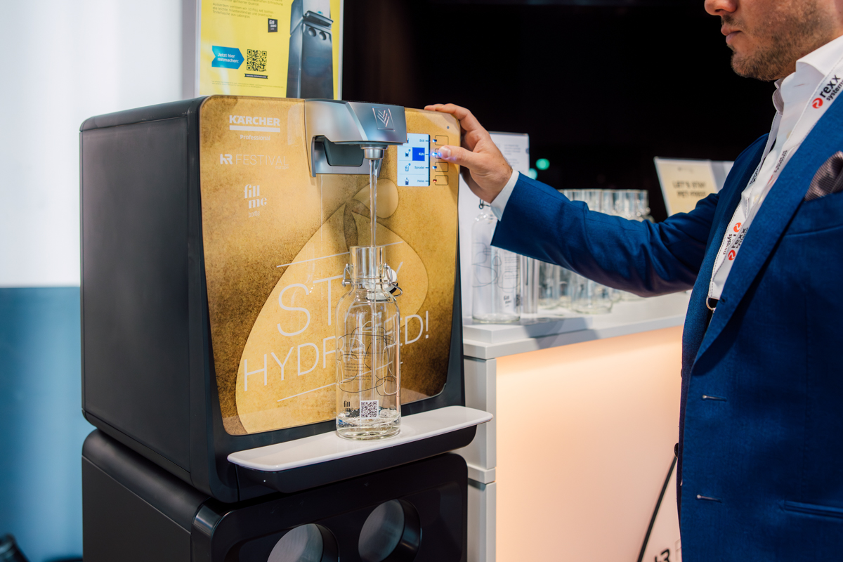 Ein Mann in blauen Anzug füllt eine Fill Me Bottle an einer Kärcher Wasserstation auf am HR Festival europe.