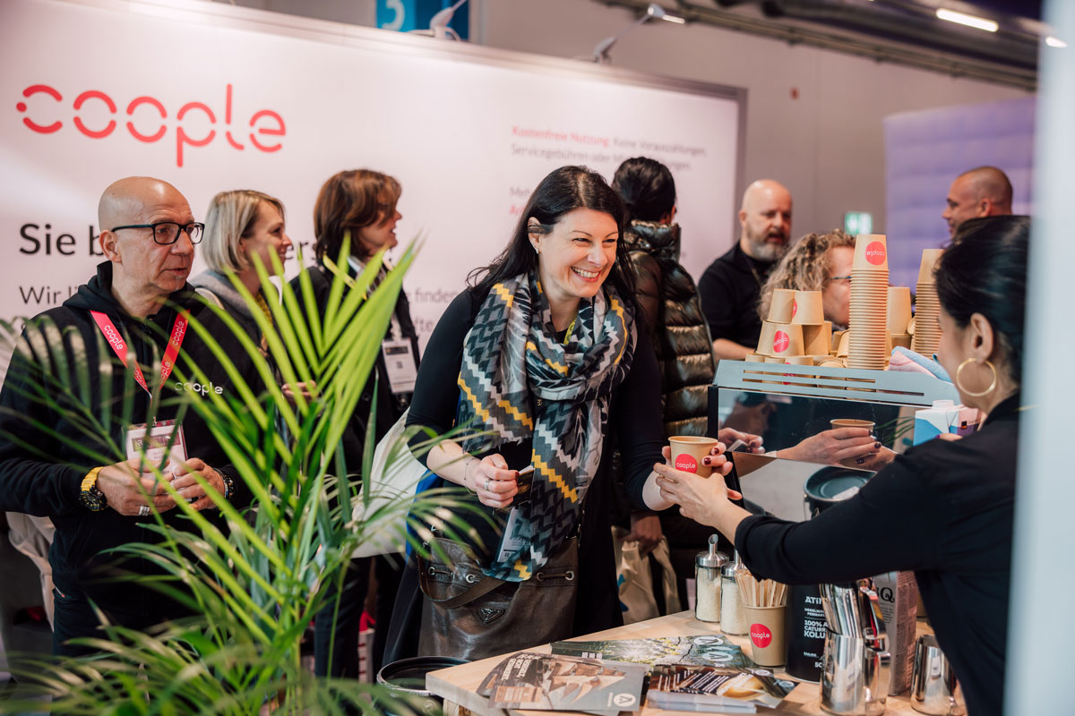 Eine Verantwortliche am Stand des Ausstellers Cooples am HR FESTIVAL europe 2024 reicht einer Besucherin einen frisch gebrühten Kaffee.