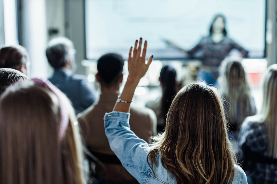 Une femme pose une question lors d'une formation en entreprise.