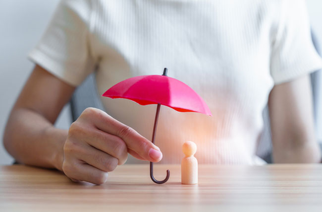 Eine Person hält einen Regenschirm über ein Figürchen, symbolisch für psychologische Sicherheit.