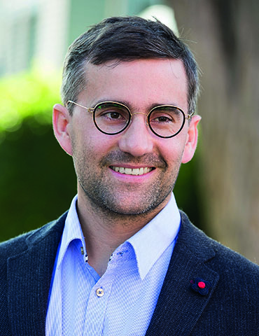 Das Bild zeigt Philippe Dutkiewicz, ein Mann mit Blazer, hellblauem Hemd, kurzen Haaren und Brille.