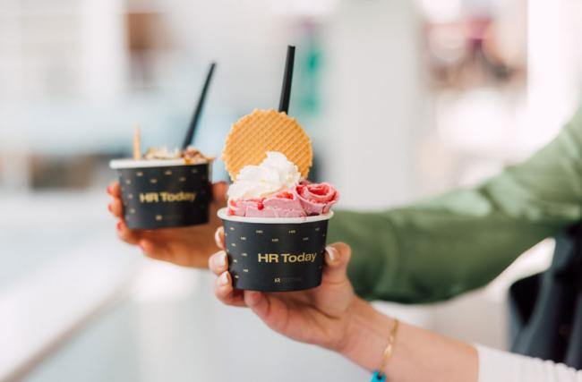 Deux femmes tiennent des gobelets de «curly ice» servis sur le stand HR Today.