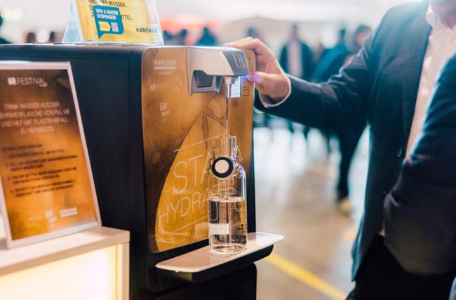 Un homme remplit une bouteille Fill me à une station d'eau Kärcher au HR FESTIVAL europe.