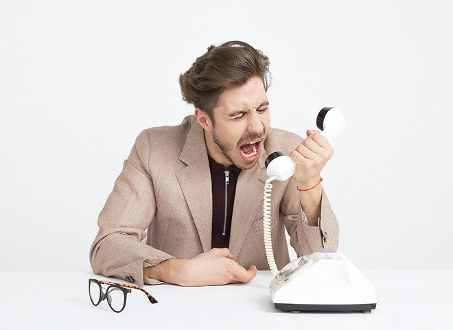Un homme en colère crie dans le combiné d'un téléphone