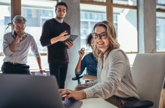 Deux hommes et deux femmes regardent un ordinateur dans un bureau