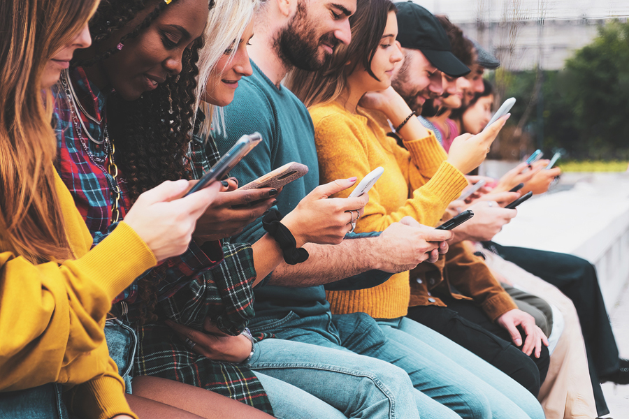 Génération Z et créativité: des jeunes assis sur un banc, téléphones en main