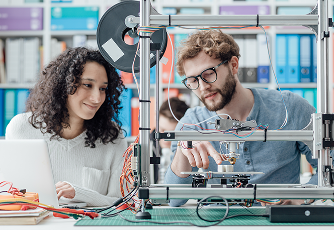 Eine Ingenieurin und ein Ingenieur besprechen einen Prototyp.