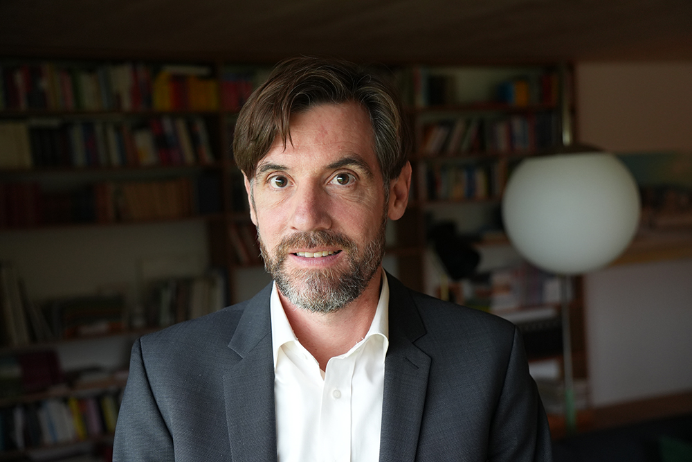 Das Bild zeigt Stefan Heer, einen Mann mit kurzen Haaren mit Seitenscheitel, dunklen Augen und kurzem Vollbart. Er trägt Hemd und Jackett.