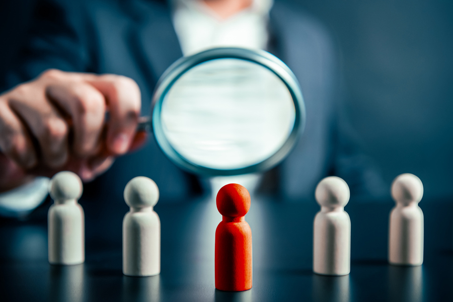 Un homme examine des pions en bois avec une loupe