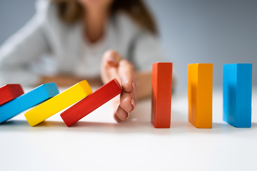 Une femme d'affaires empêche des dominos colorés de tomber