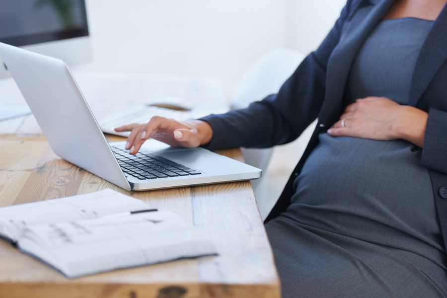 Une femme enceinte travaille sur son ordinateur portable au bureau