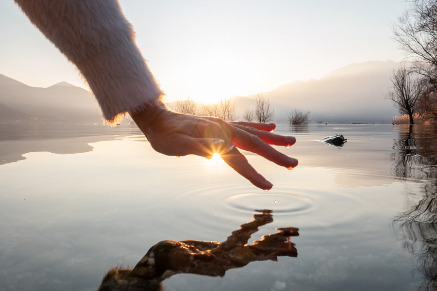 Une personne effleure la surface d'un lac au coucher du soleil en Suisse