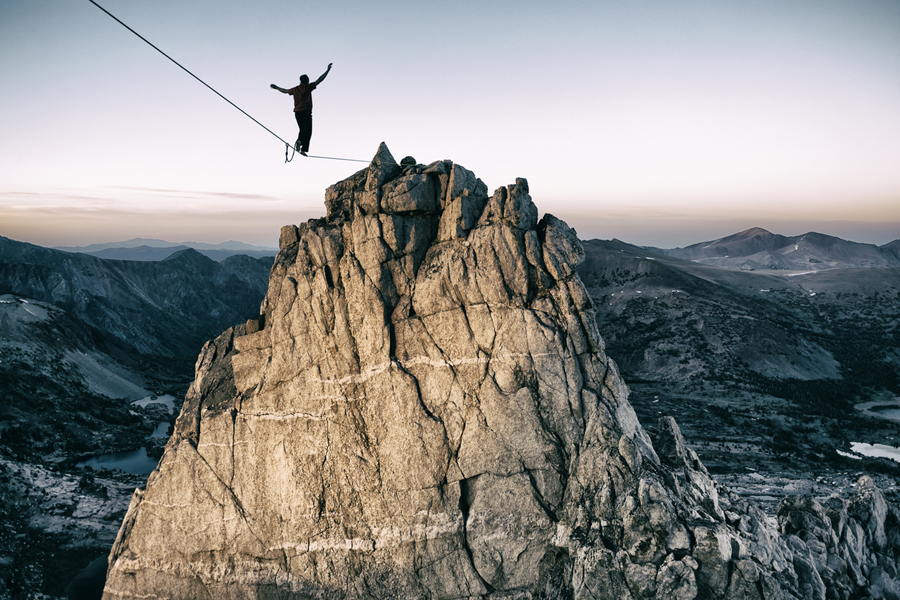 Un homme avance sur une corde raide en montagne