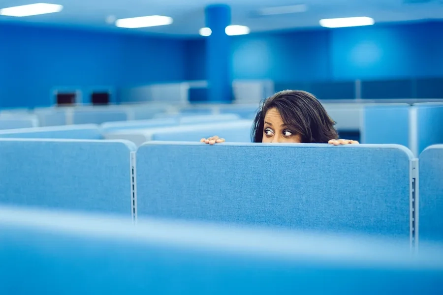 Logiciels de surveillance au travail: contrôle versus confiance. Une femme regarde par-dessus une paroi dans un bureau.