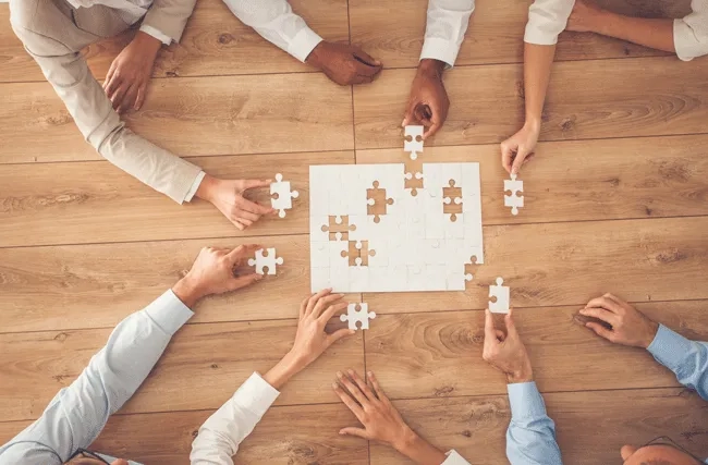 Gruppe von Mitarbeitenden setzt Puzzleteile zusammen
