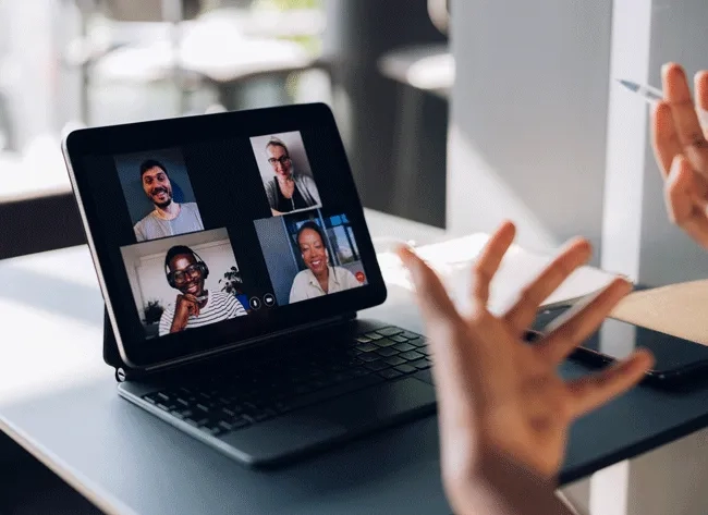 Eine Mitarbeiterin gestikuliert, während sie mit ihren Arbeitskollegen via Video kommuniziert