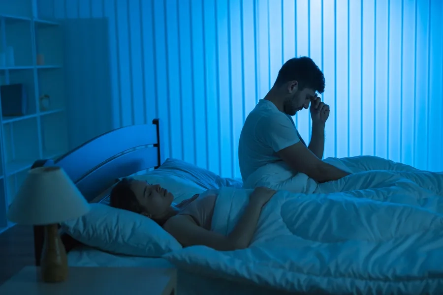 Sommeil et leadership: un homme se tient dans son lit souffrant d'insomnie