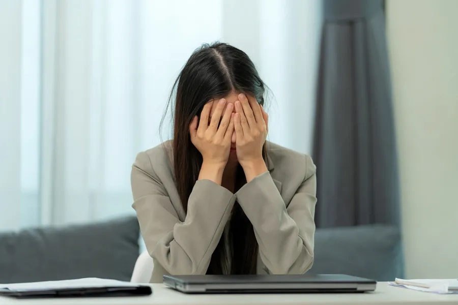 Une femme d'affaires se tient la tête dans un bureau