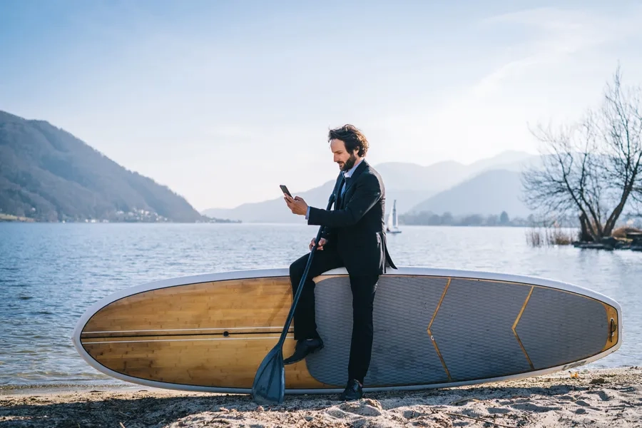 Un homme d'affaires regarde son téléphone portable au bord du lac de Lugano