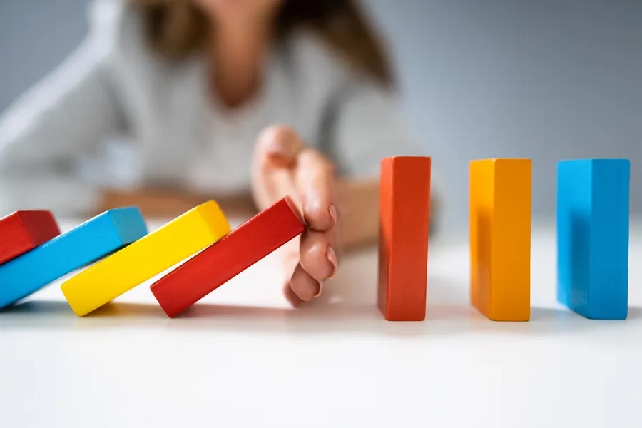 Une femme d'affaires empêche des dominos colorés de tomber