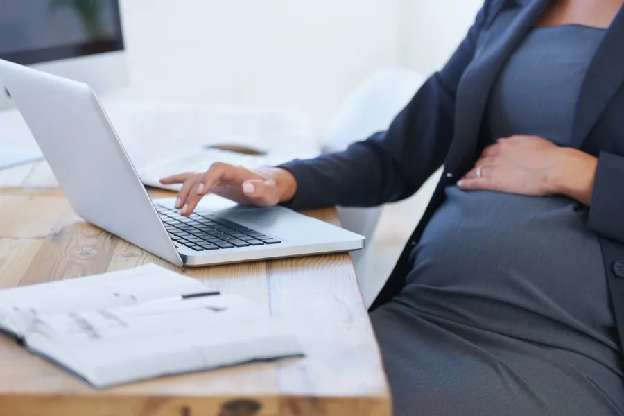 Une femme enceinte travaille sur son ordinateur portable au bureau