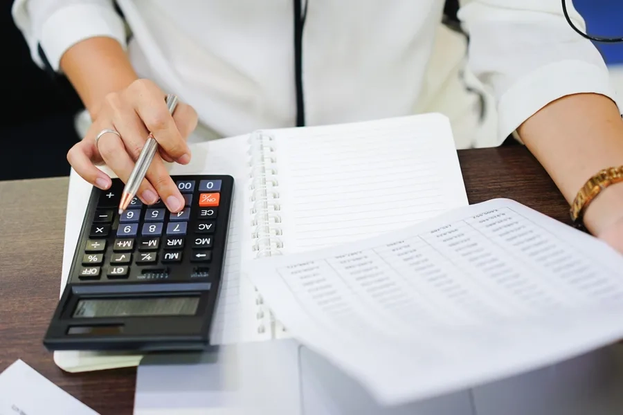 Gros plan sur la main d'une comptable senior calculant des coûts 