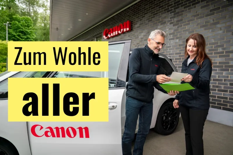 Redaktionelle Grafik mit dem Titeltext «Zum Wohle aller» auf gelben Balken links: Zwei Personen in Canon-Fleecejacken stehen vor einem Canon-Firmenfahrzeug und dem Canon-Gebäude und schauen gemeinsam auf ein Dokument; im Hintergrund ist das rote Canon-Leuchtschild an der Fassade sichtbar.