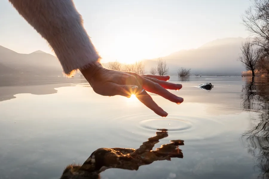 Une personne effleure la surface d'un lac au coucher du soleil en Suisse